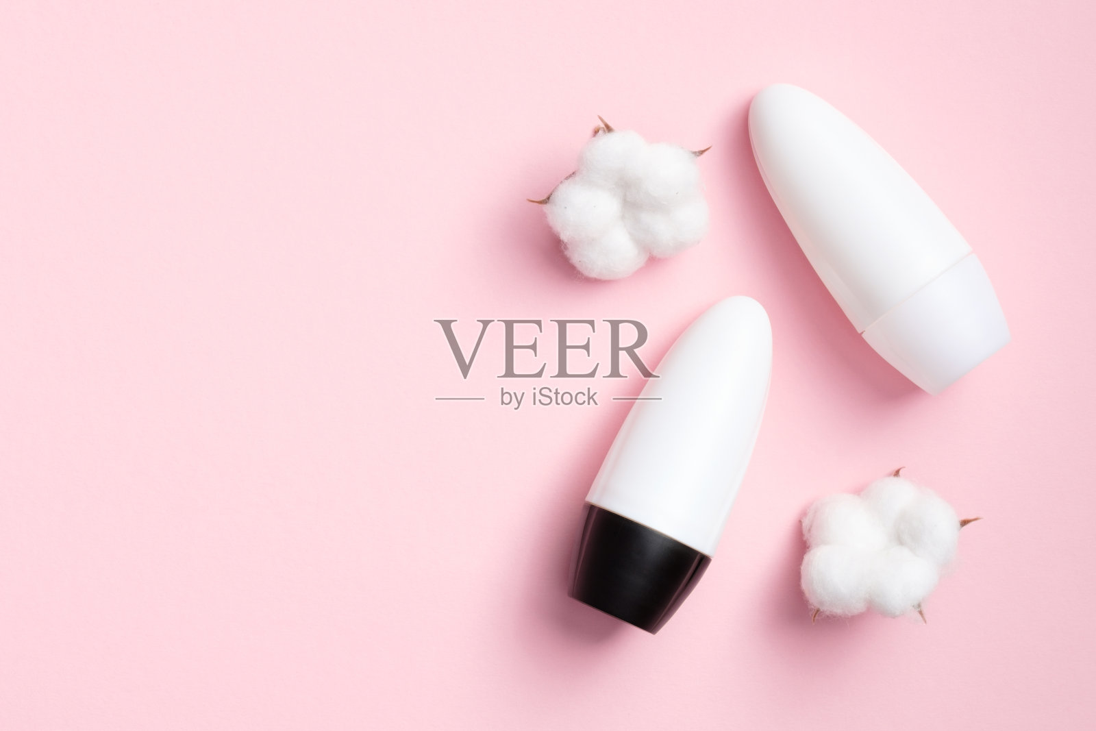 除臭剂瓶模型与棉花花在粉红色的背景。平躺，俯视图。空白止汗包装，防汗产品概念照片摄影图片