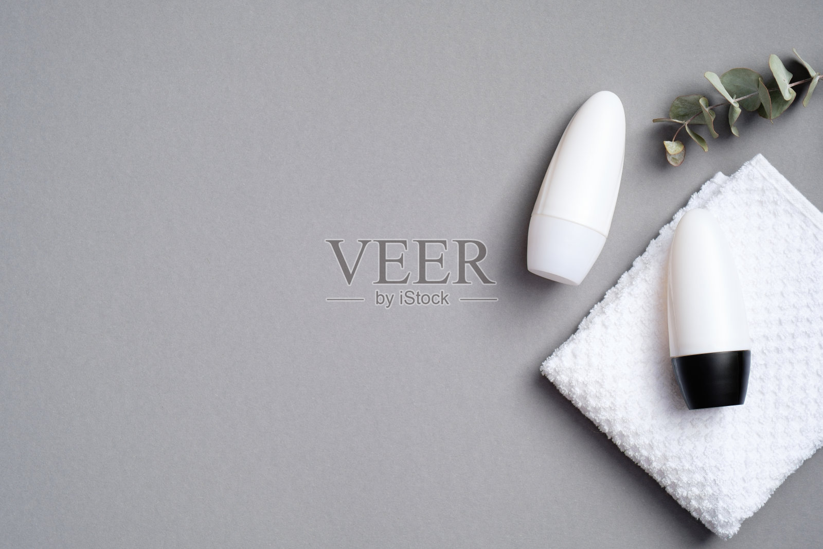 在灰色背景上使用桉树和毛巾擦除除汗剂。平躺，俯视图。除臭剂包装模型照片摄影图片