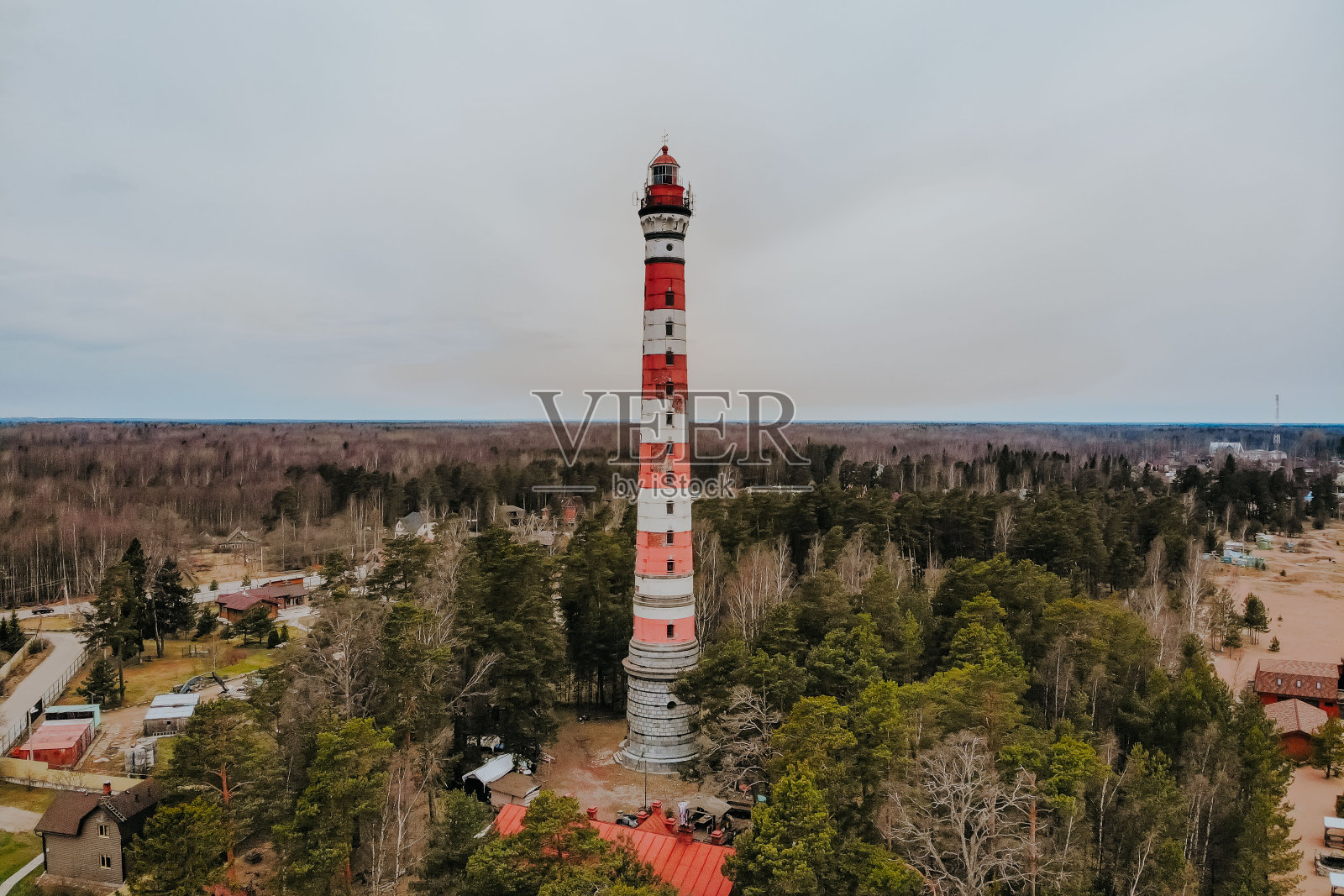 海边有灯塔。湖面上有暴风雨天气。恶劣天气下的沙滩。白色灯塔，红色顶部的岩石。照片摄影图片