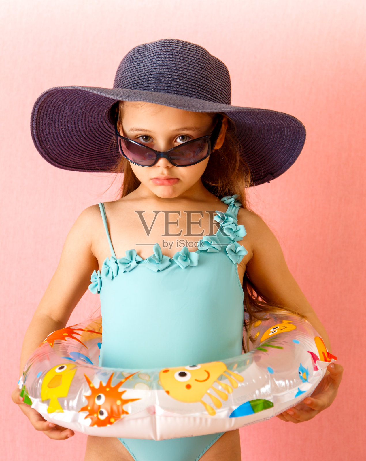 小女孩穿着泳衣，戴着帽子和眼镜，情绪激动照片摄影图片