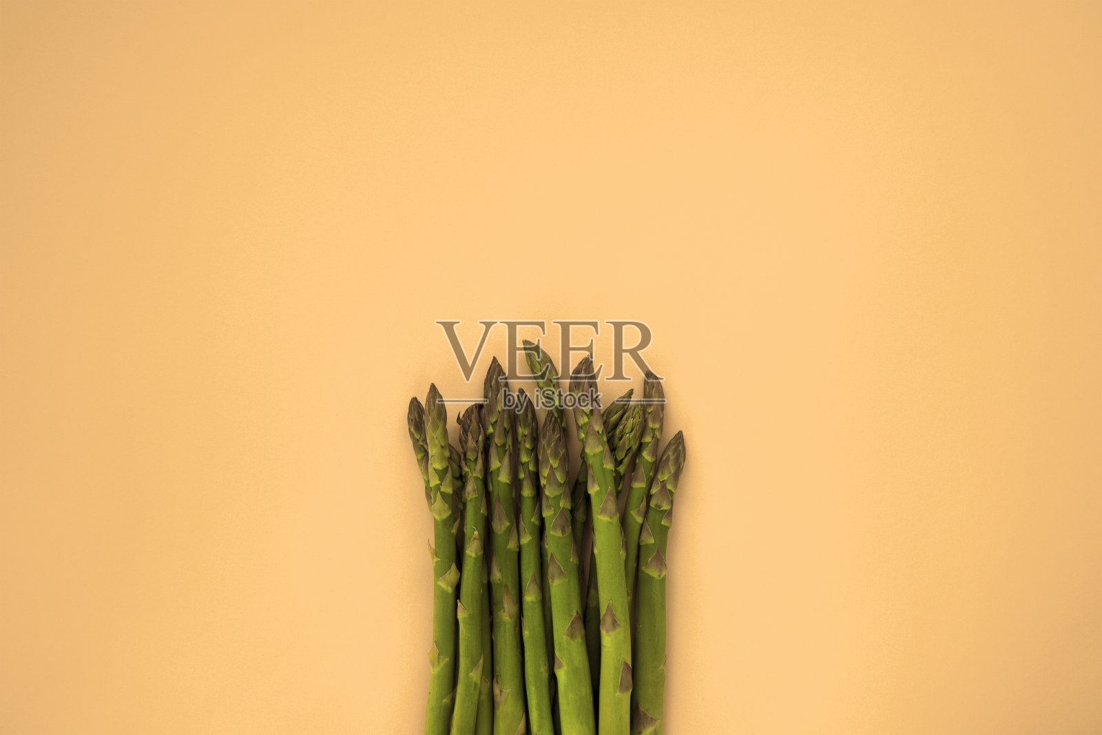 橙色背景下的新鲜绿芦笋。俯视图照片摄影图片
