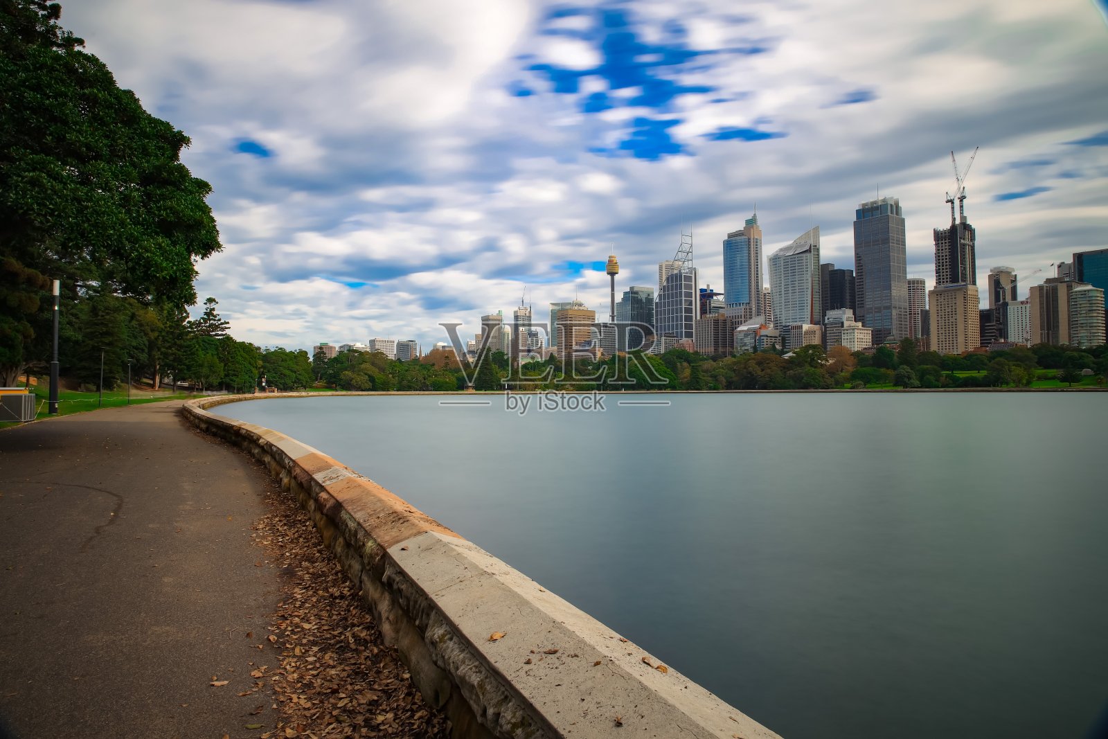 在一个多云的下午，长时间曝光在悉尼港，美丽的岩石在前景，柔软的海浪冲击海岸和美丽的海港前海岸为背景照片摄影图片