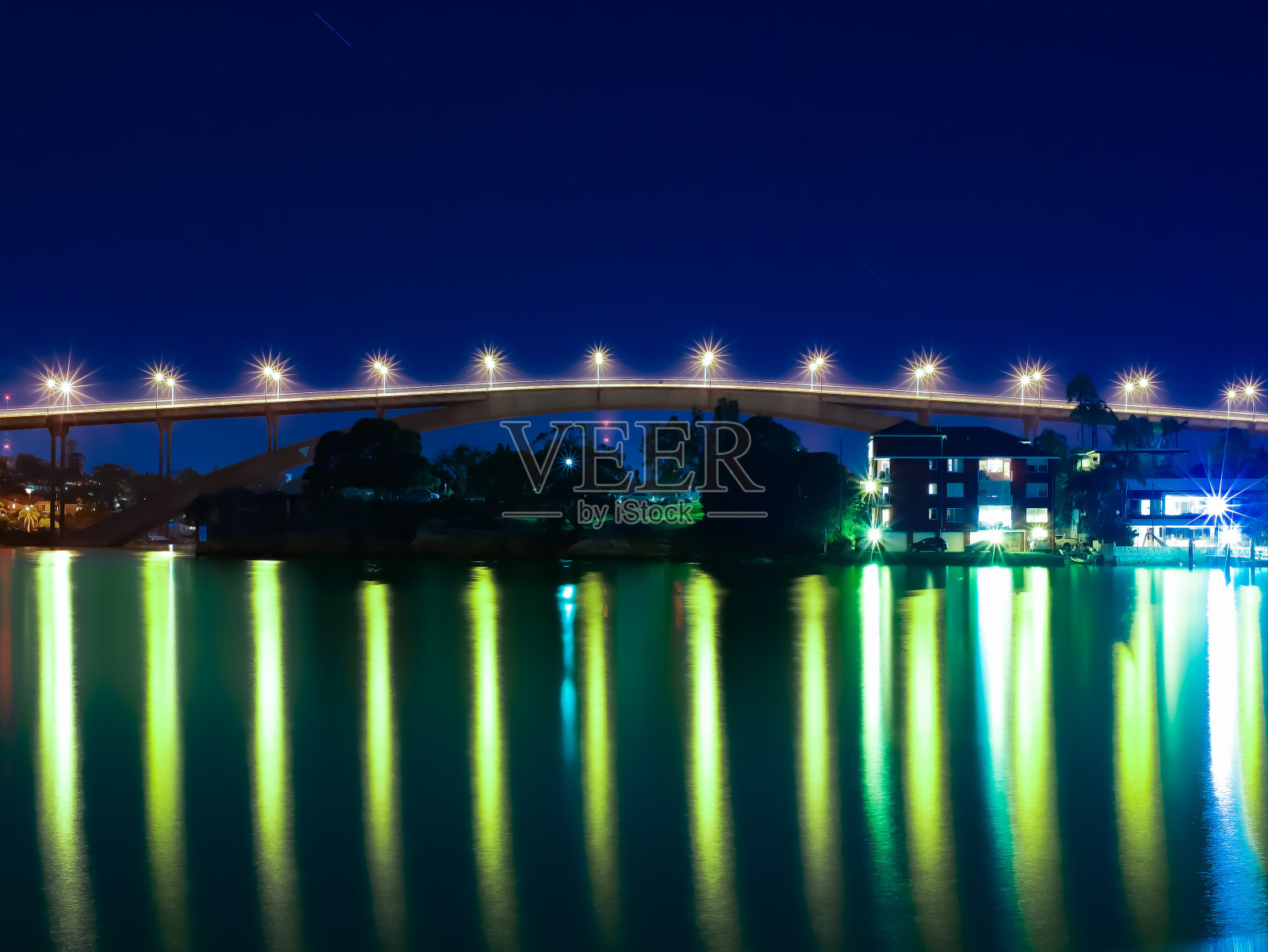 在澳大利亚悉尼的格拉迪斯维尔大桥被明亮的灯光和平静的港口水域照亮照片摄影图片