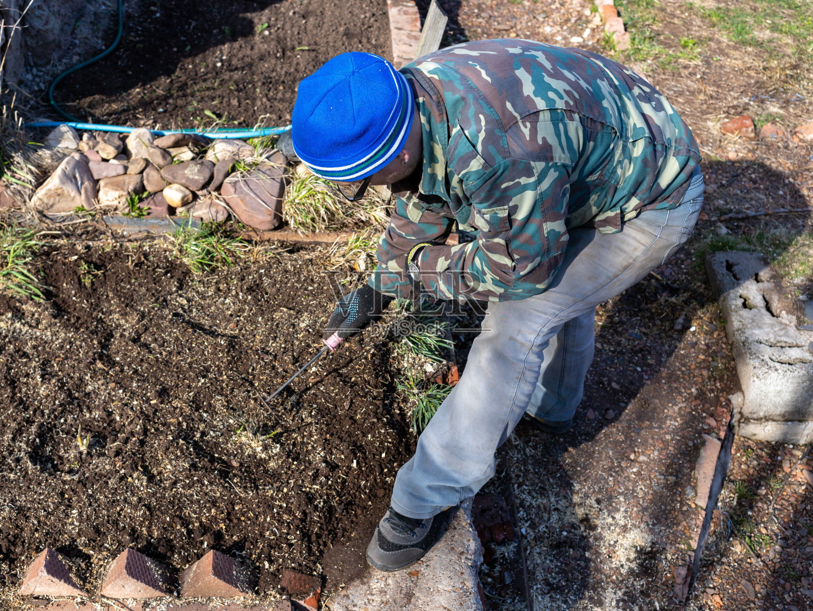 一个男人，一个欧洲白人，穿着园艺工作服，手里拿着一个工具。照片摄影图片