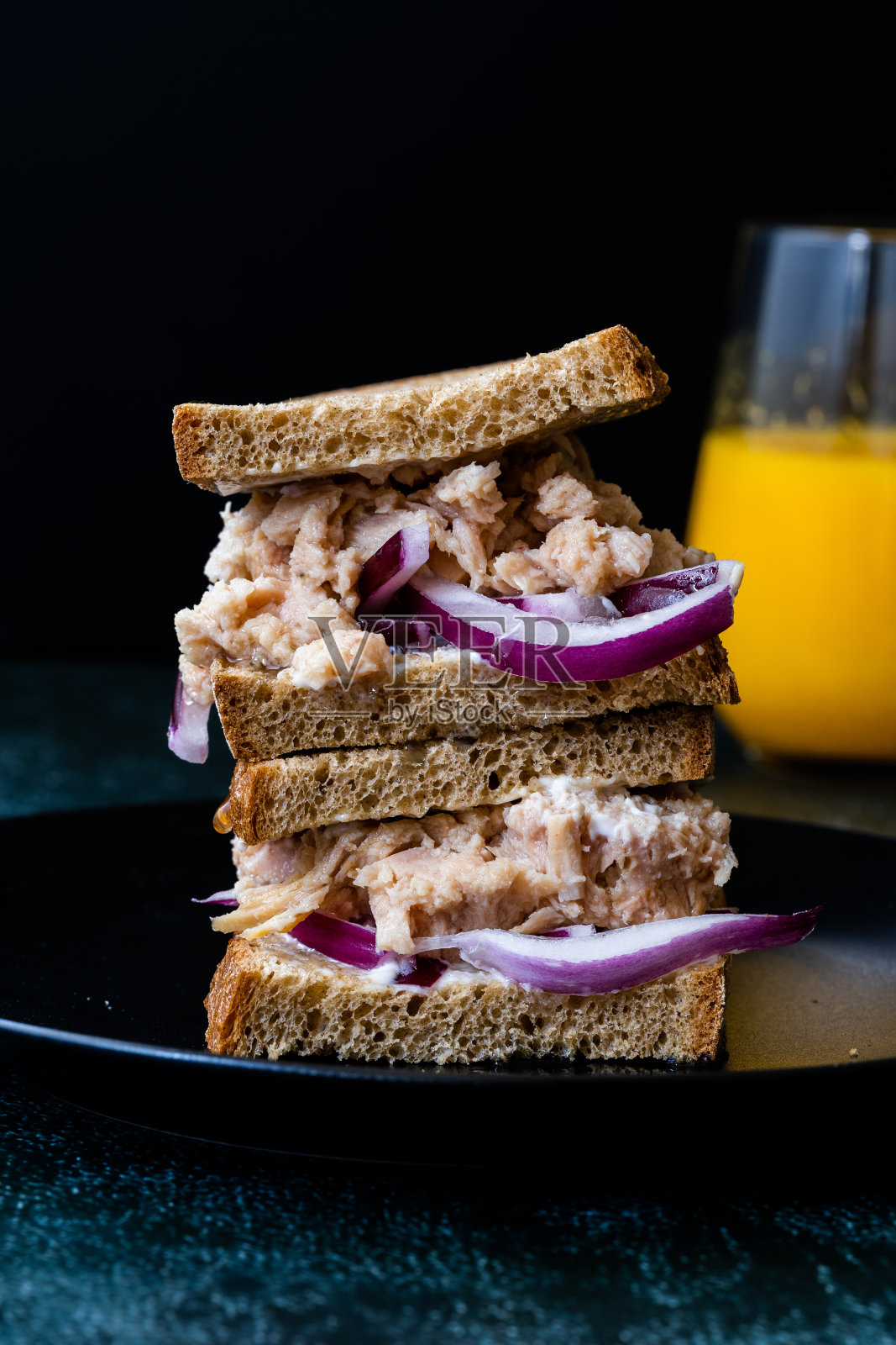金枪鱼三明治配红洋葱，蛋黄酱，杂粮轻吐司面包和橙汁。照片摄影图片