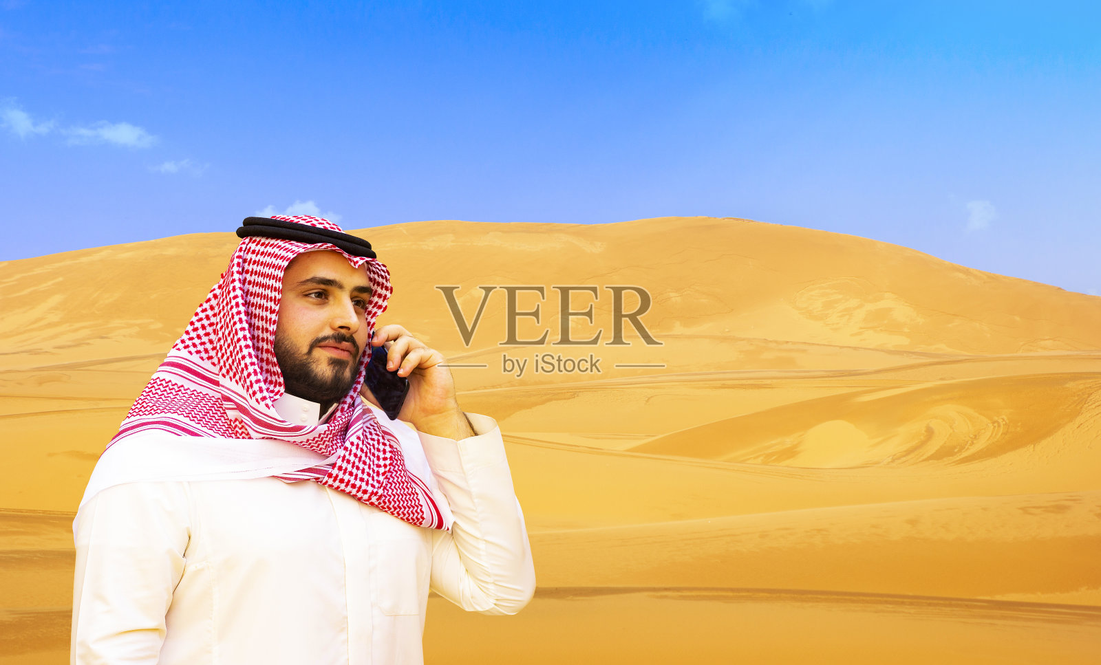 阿拉伯男子在沙漠背景上使用手机照片摄影图片