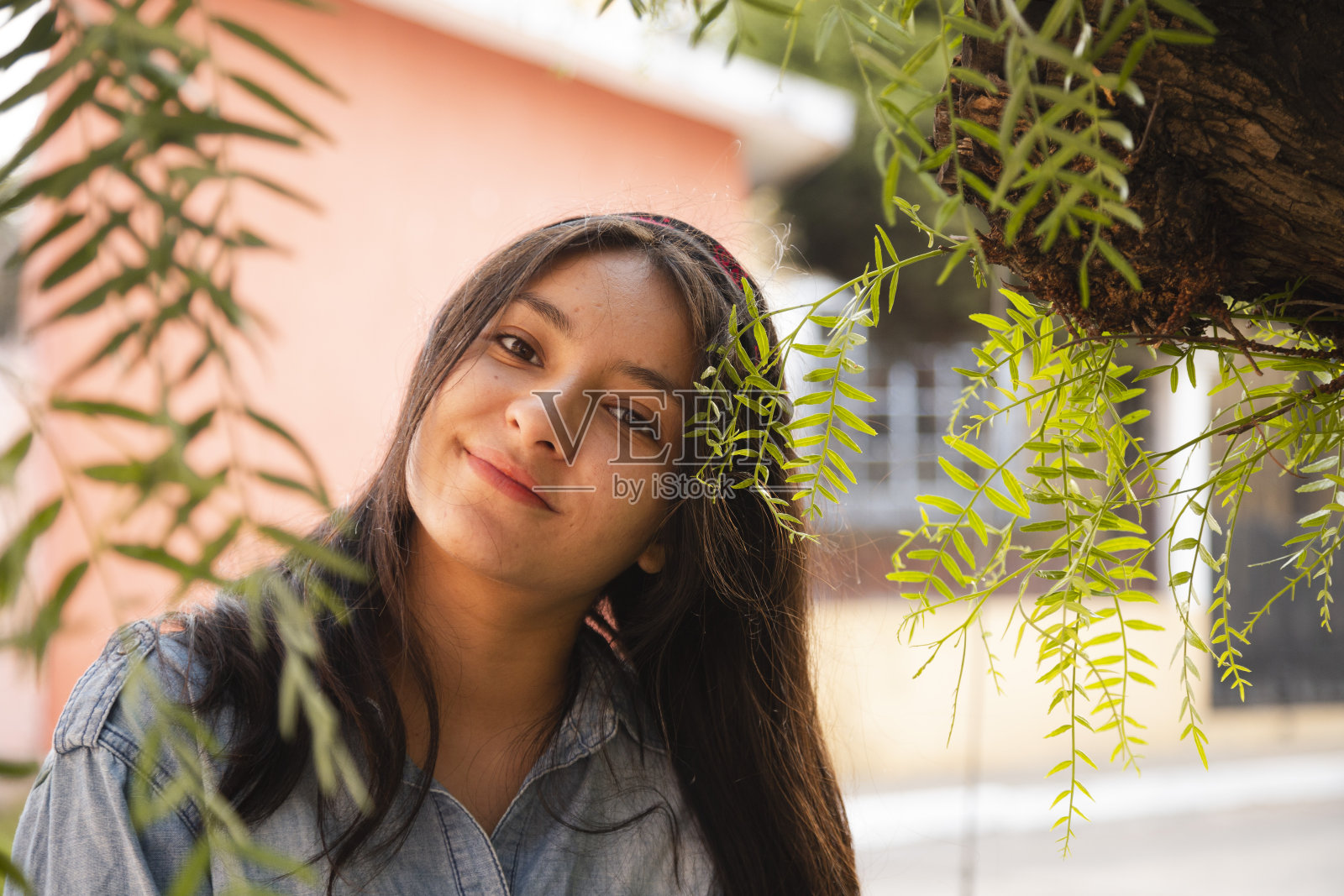 西班牙妇女的肖像在树枝看相机-拉丁妇女微笑随意在街道上照片摄影图片