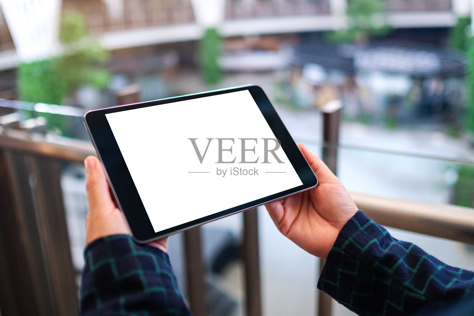 一个女人拿着黑色平板电脑和空白的白色桌面屏幕在室内照片摄影图片