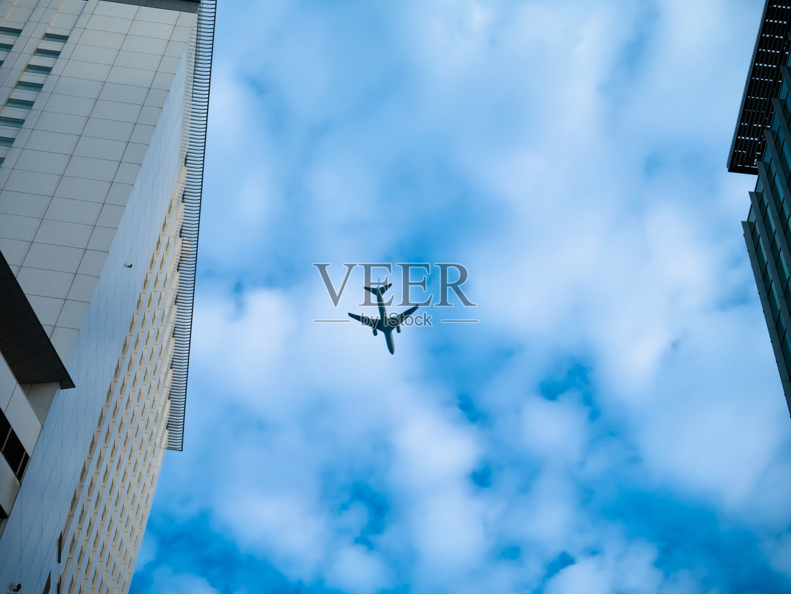 在大楼上空低空飞行的客机照片摄影图片