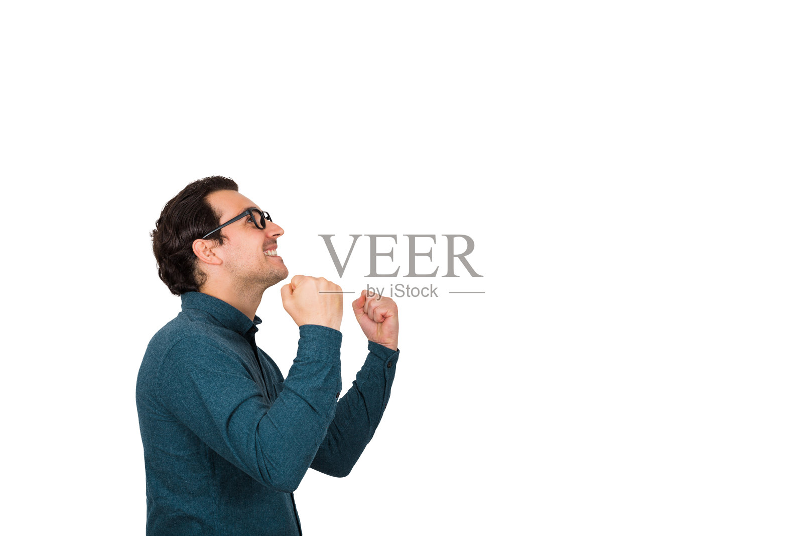 侧面的成功的年轻商人保持拳头紧，庆祝胜利，孤立的白色背景与复制空间。商务人员戴着眼镜，高兴地抬起头。成就的概念。照片摄影图片