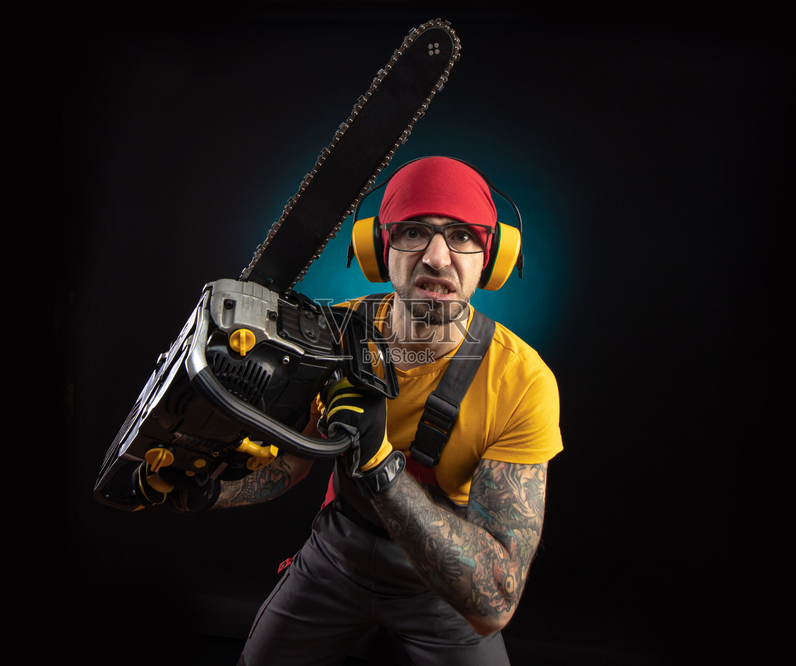 一个穿着防护服的人在黑色背景上拿着电锯照片摄影图片