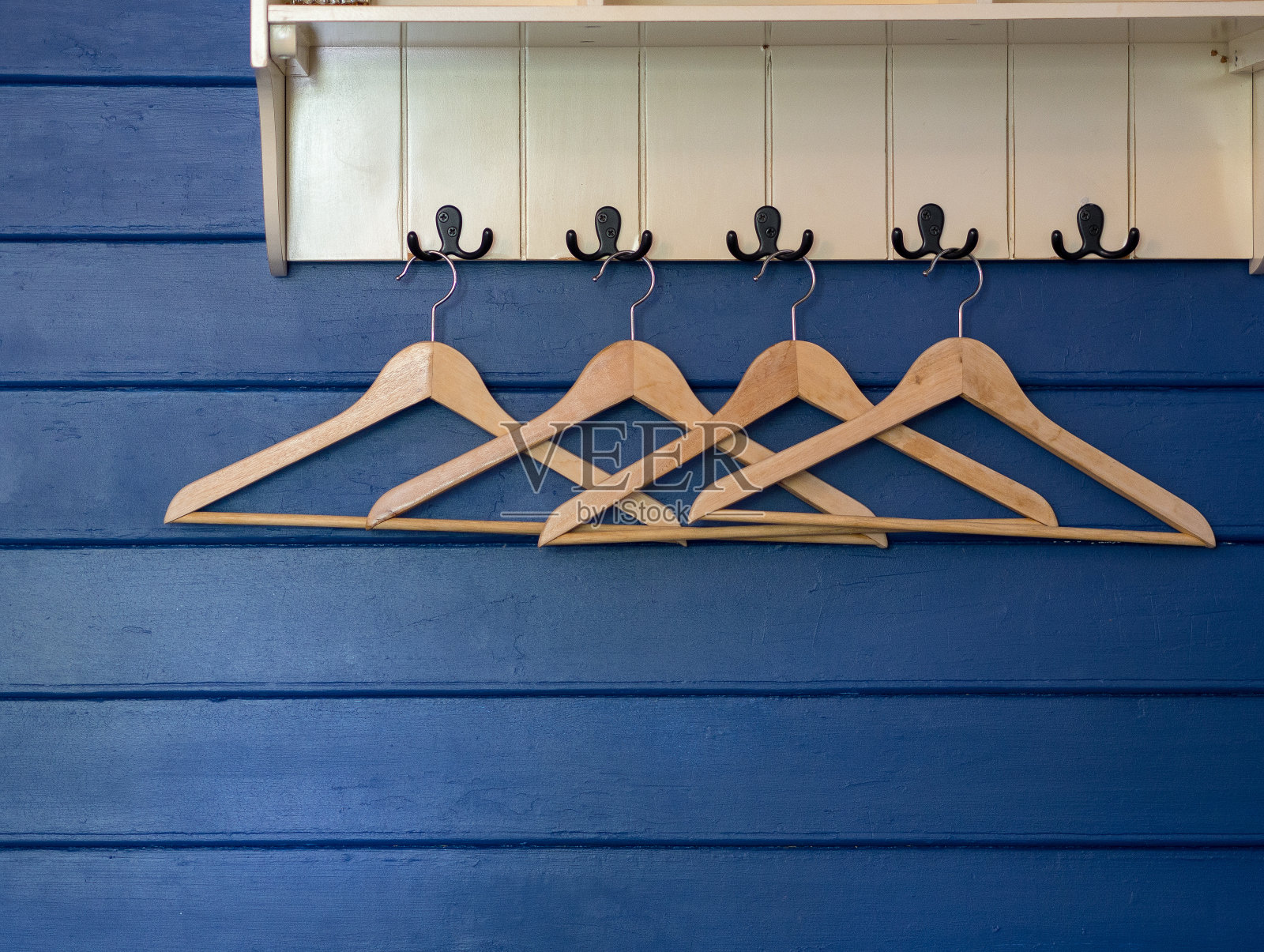 在漂亮的房间度假村的蓝色墙壁上的木衣架。照片摄影图片
