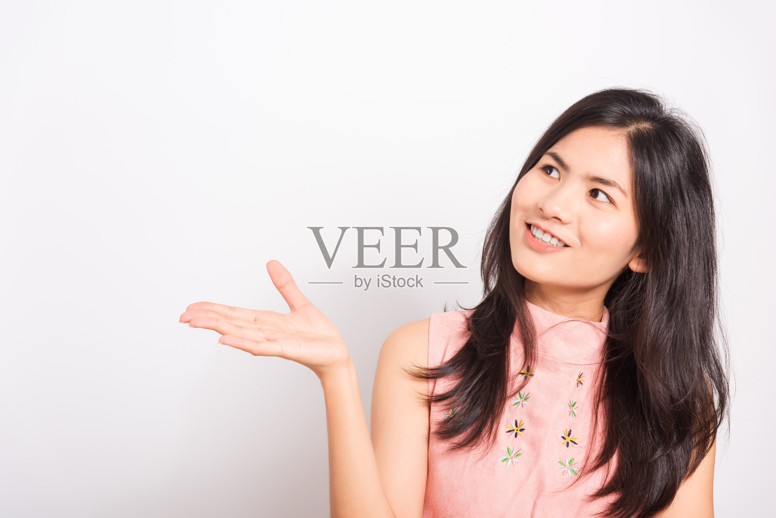 肖像亚洲美丽的年轻女子站着，她的手展示产品和看产品，拍摄照片的工作室在白色的背景，有复制空间照片摄影图片