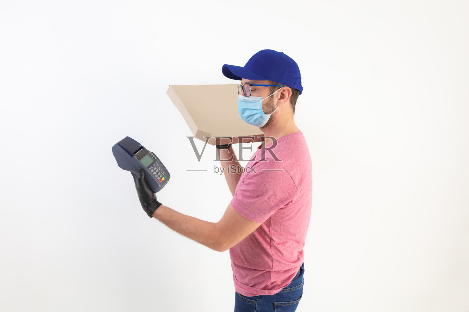 戴着防护面具的快递员拿着披萨盒和POS机进行非接触式支付。照片摄影图片
