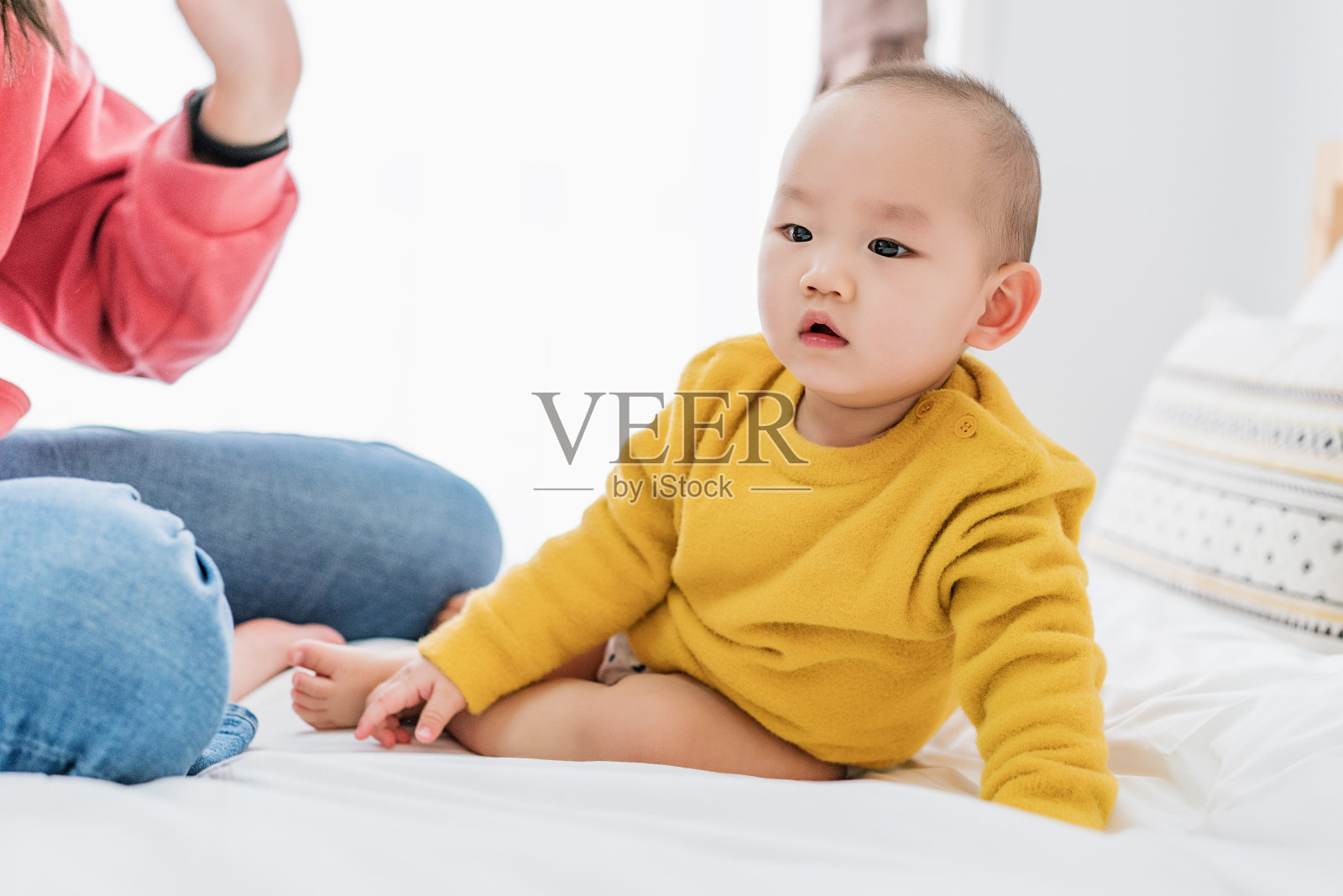 一位年轻的亚洲妇女正在为她的儿子换衣服照片摄影图片