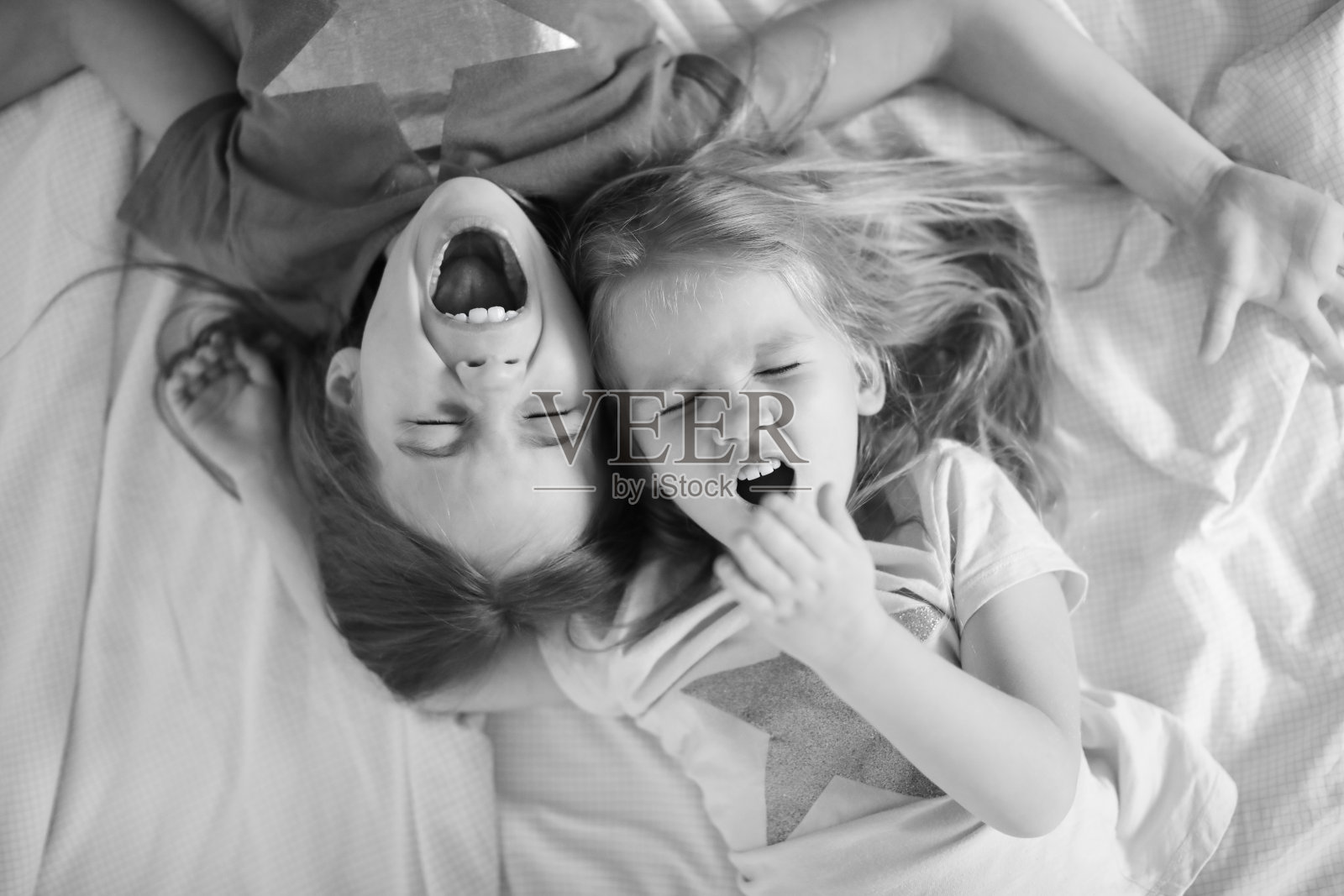 两个姐妹躺在地板上打哈欠。黑白。照片摄影图片