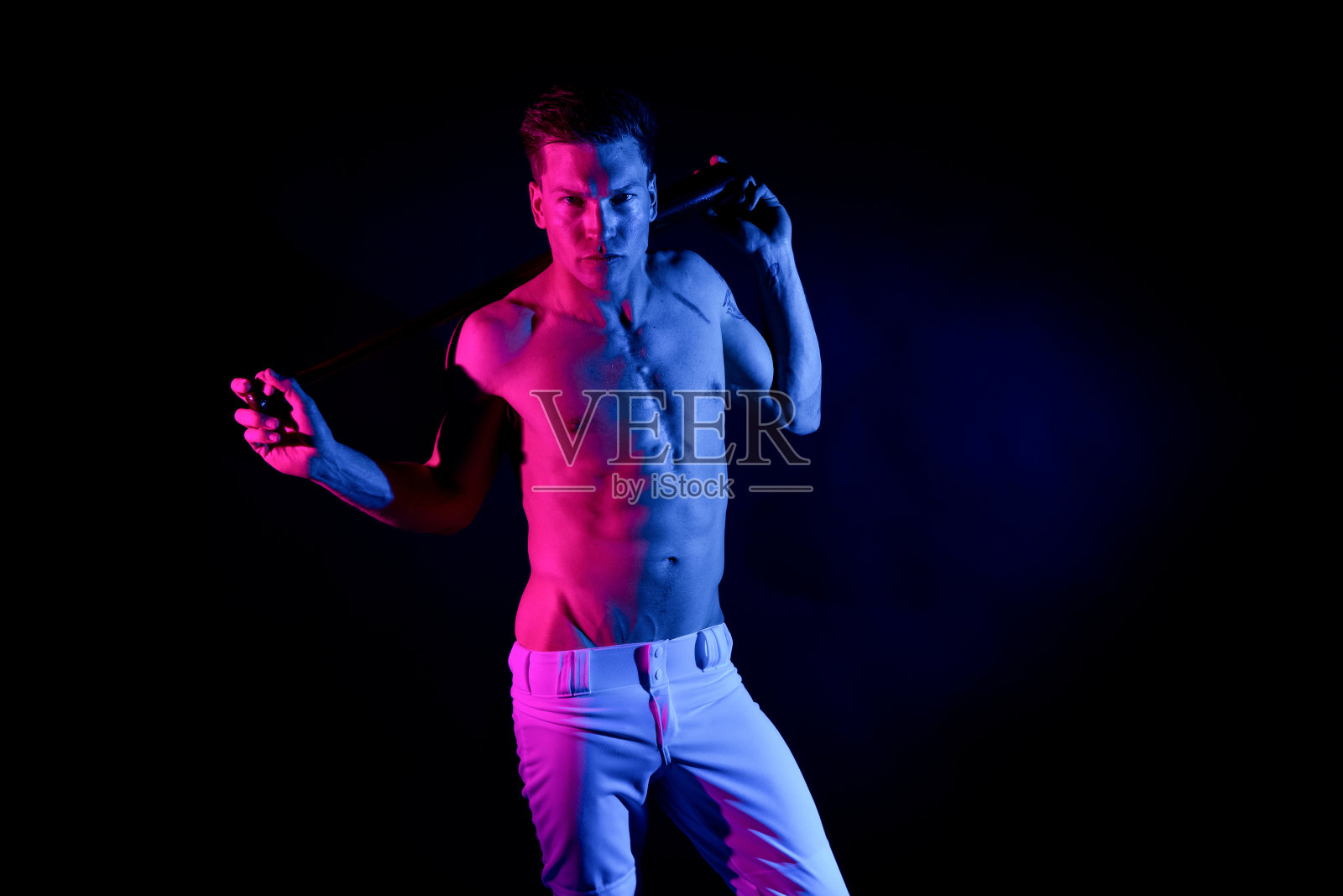 白人年轻男性棒球运动员在黑人背景前面，拿着运动球棒照片摄影图片