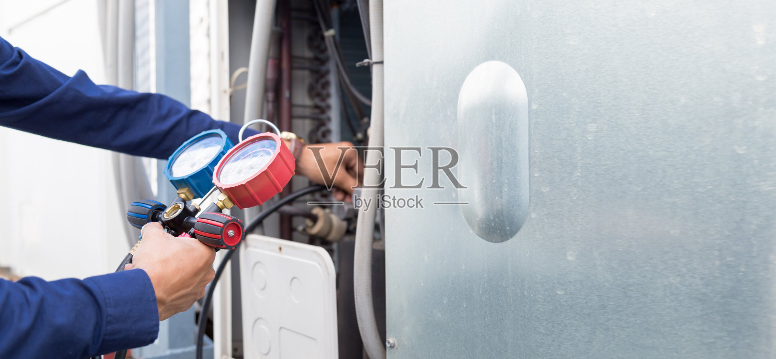 技术人员正在检查空调，测量设备是否充空调。照片摄影图片