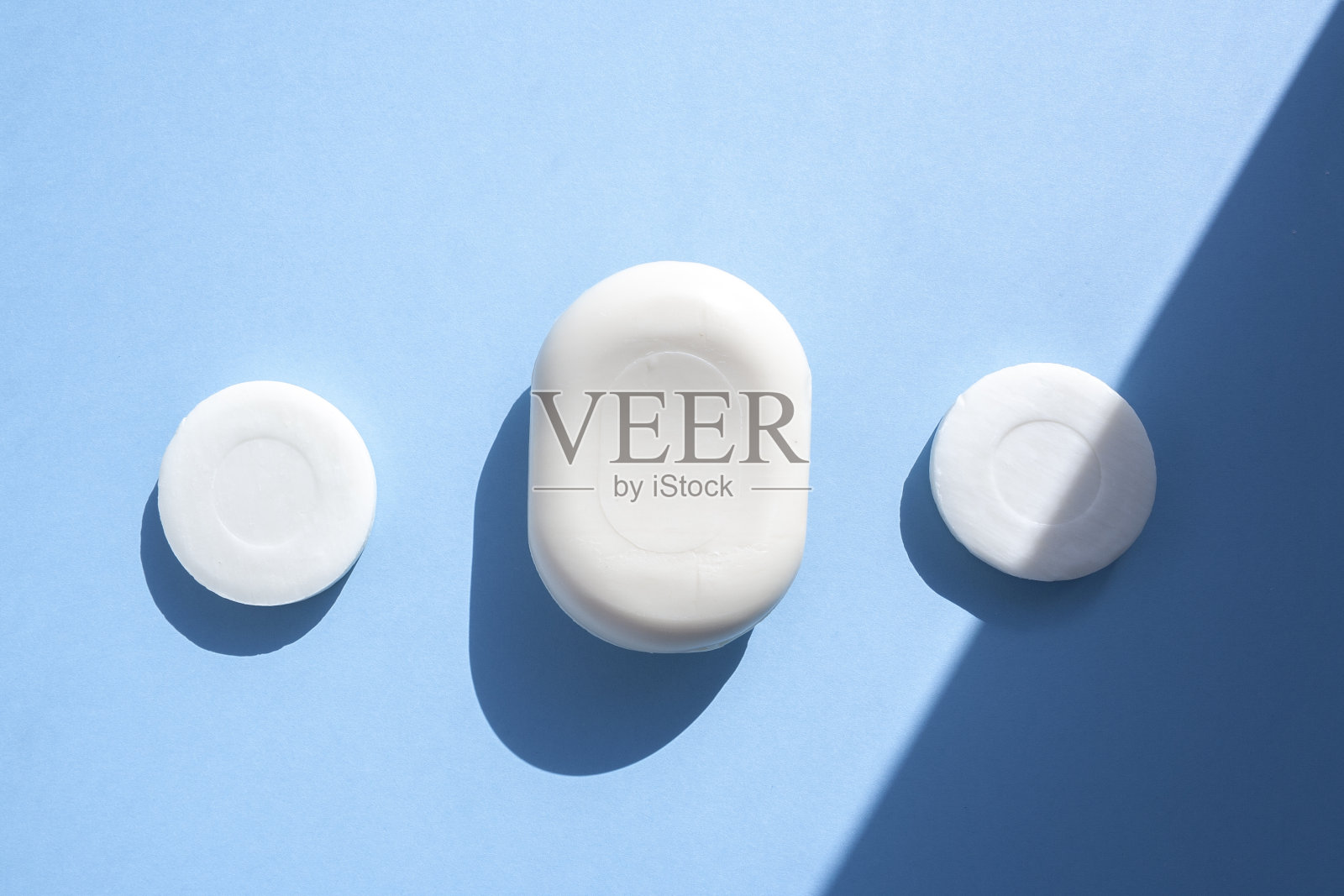 三件肥皂俯视图在蓝色背景与时尚照明从太阳。洗你的手。肥皂防细菌和病毒。遵守卫生和无菌，抗击冠状病毒。照片摄影图片