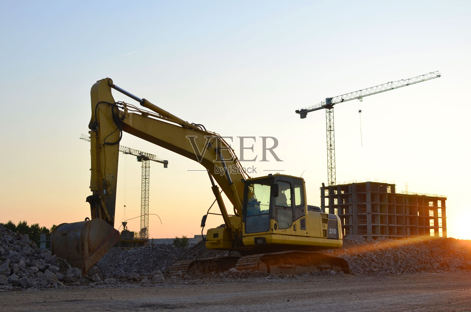 挖掘机用大铁斗在建筑工地进行道路施工。用挖土机挖地基，铺设雨水管道。安装水总管系统。照片摄影图片