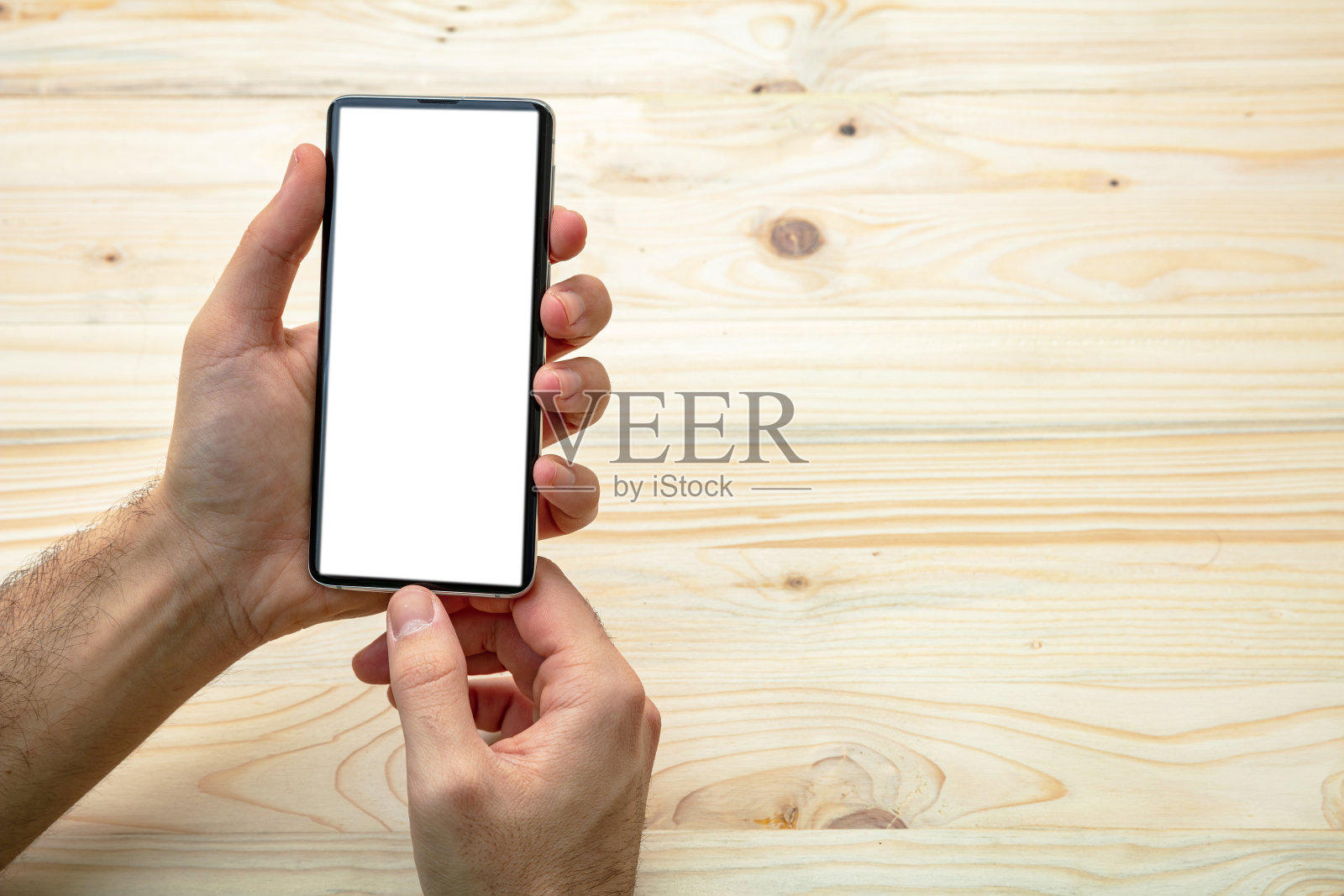 一个男人拿着一个黑屏，木制背景的智能手机照片摄影图片