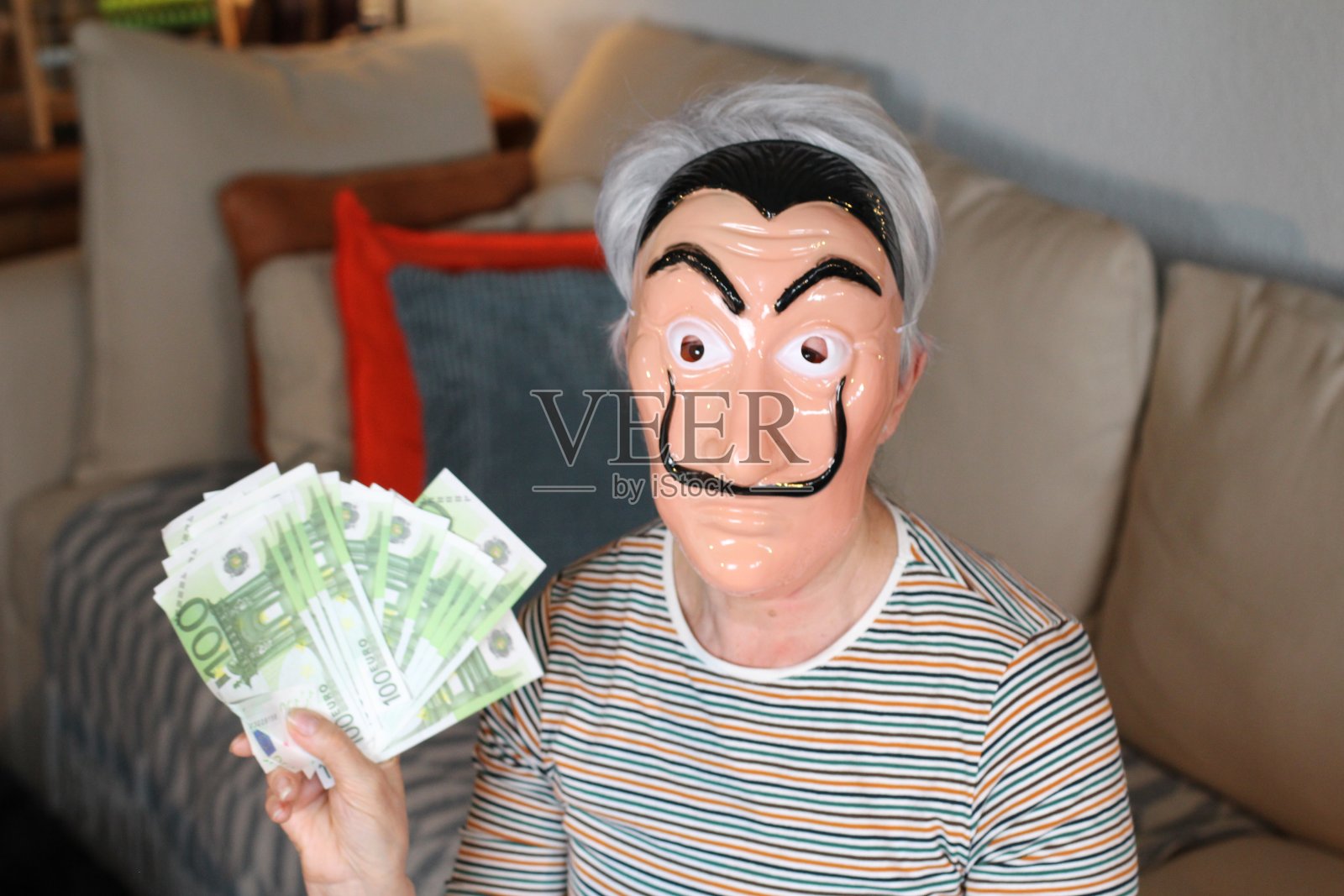 戴着面具，拿着欧元的妇女照片摄影图片