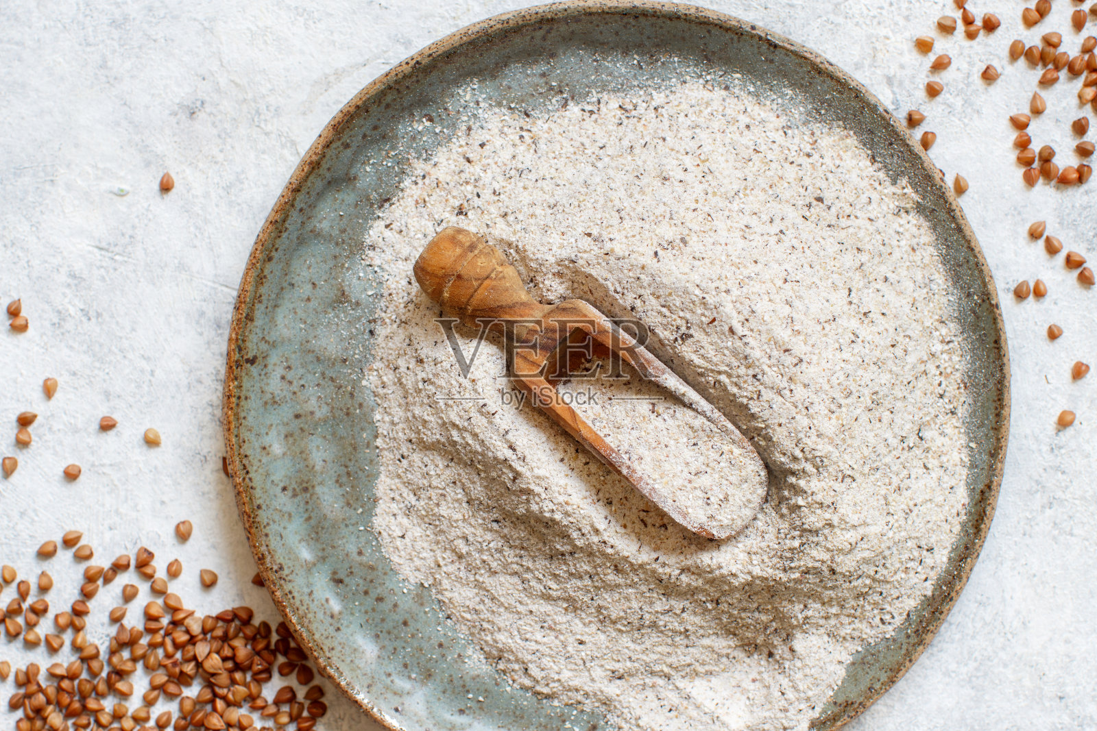 荞麦面粉在一个盘子里，用勺子和荞麦谷物照片摄影图片