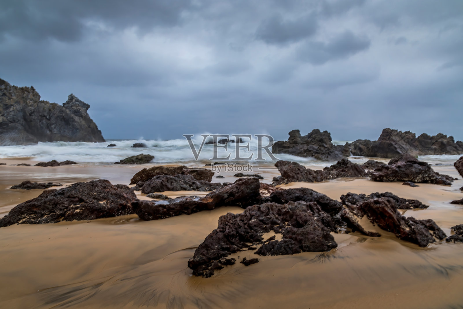澳大利亚新南威尔士州骆驼岩湾海滩上的岩石。这是一个多云多风的夏天，海面波涛汹涌。照片摄影图片