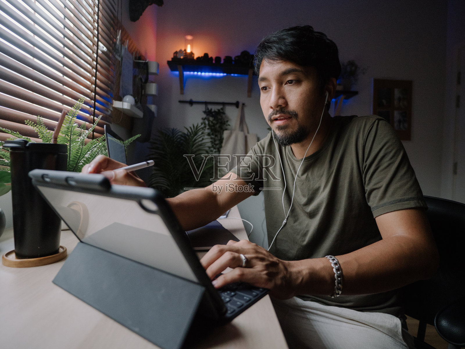 成熟的亚洲男人在现代家庭办公室工作的数字平板电脑。照片摄影图片