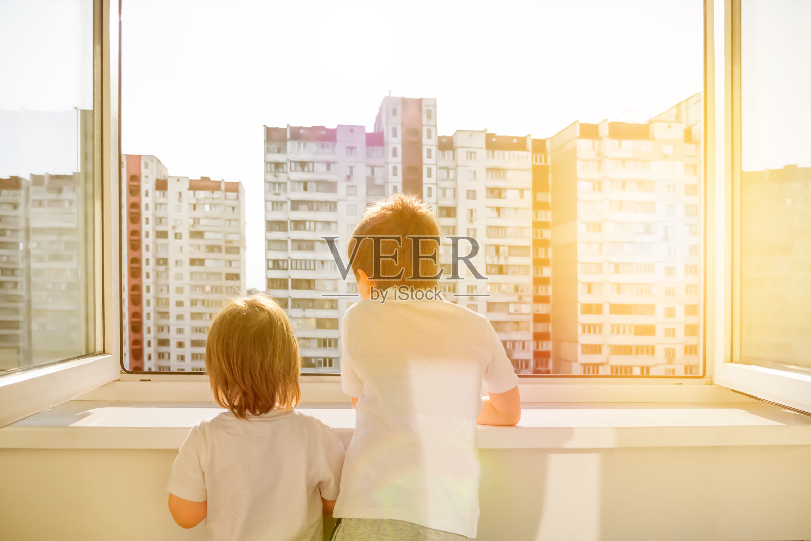 孩子们在阳台上。闭关锁国则和冠状病毒摧毁。人们在家中隔离一段时间。阳台上的兄弟姐妹看着窗外。与外界隔绝呆在家里。预防措施照片摄影图片