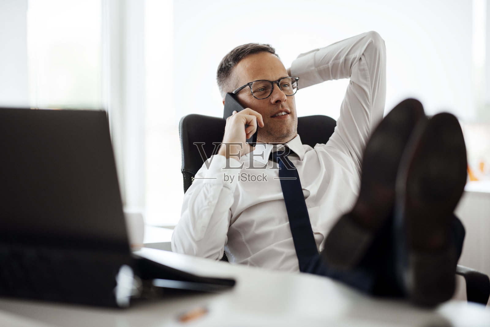 放松的年轻人与电话坐在办公室库存照片照片摄影图片