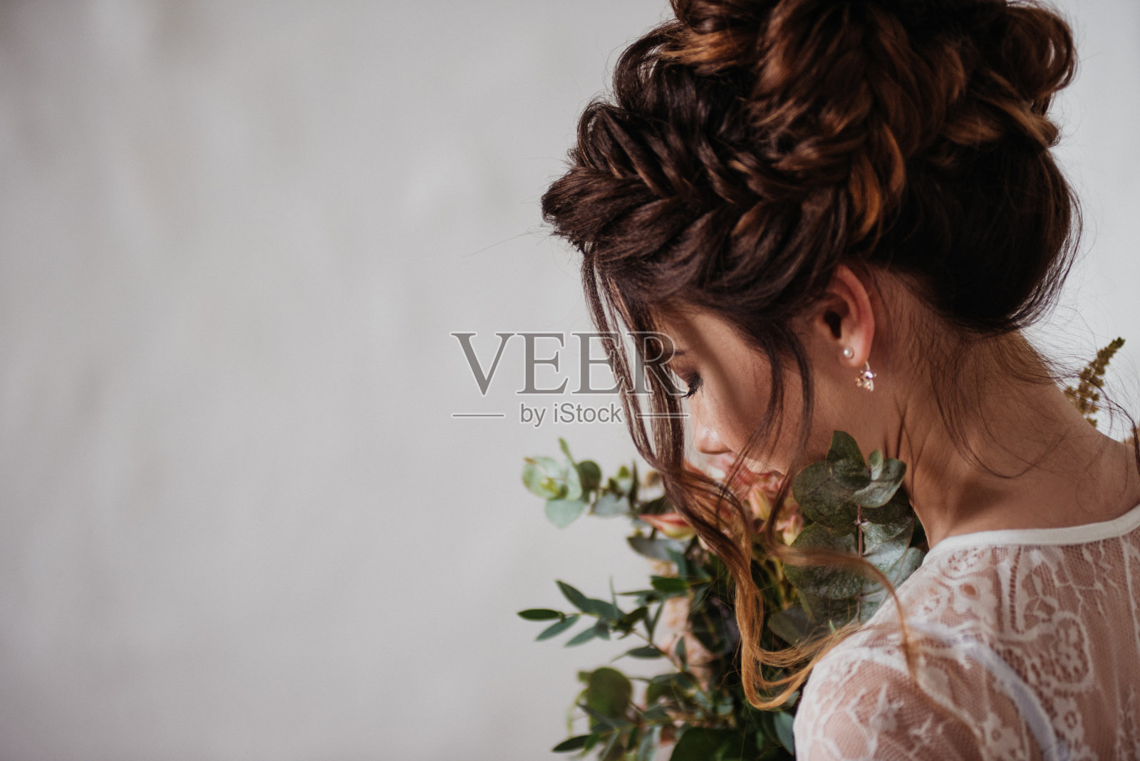 清晨，新娘穿着透明的睡衣聚集在一起。非常漂亮的粉色婚礼花束。时髦的发型，辫子。纹理的墙照片摄影图片