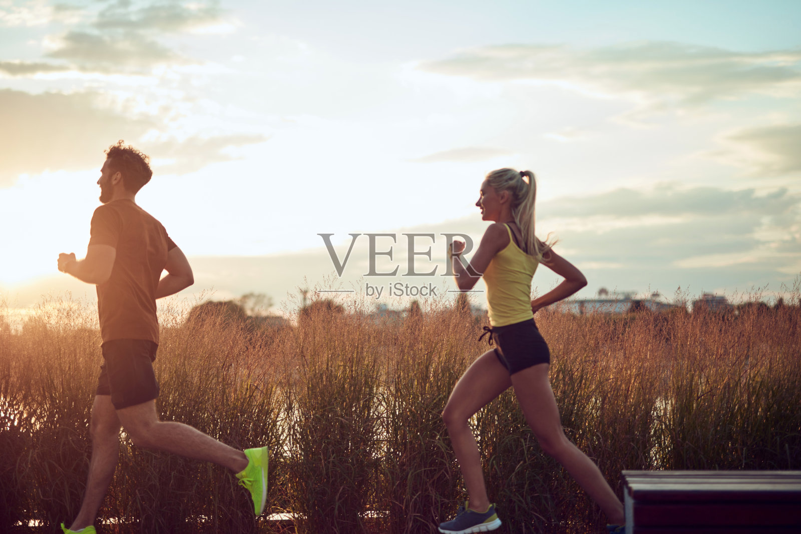 现代女人和男人在河边的城市环境中慢跑/锻炼。照片摄影图片