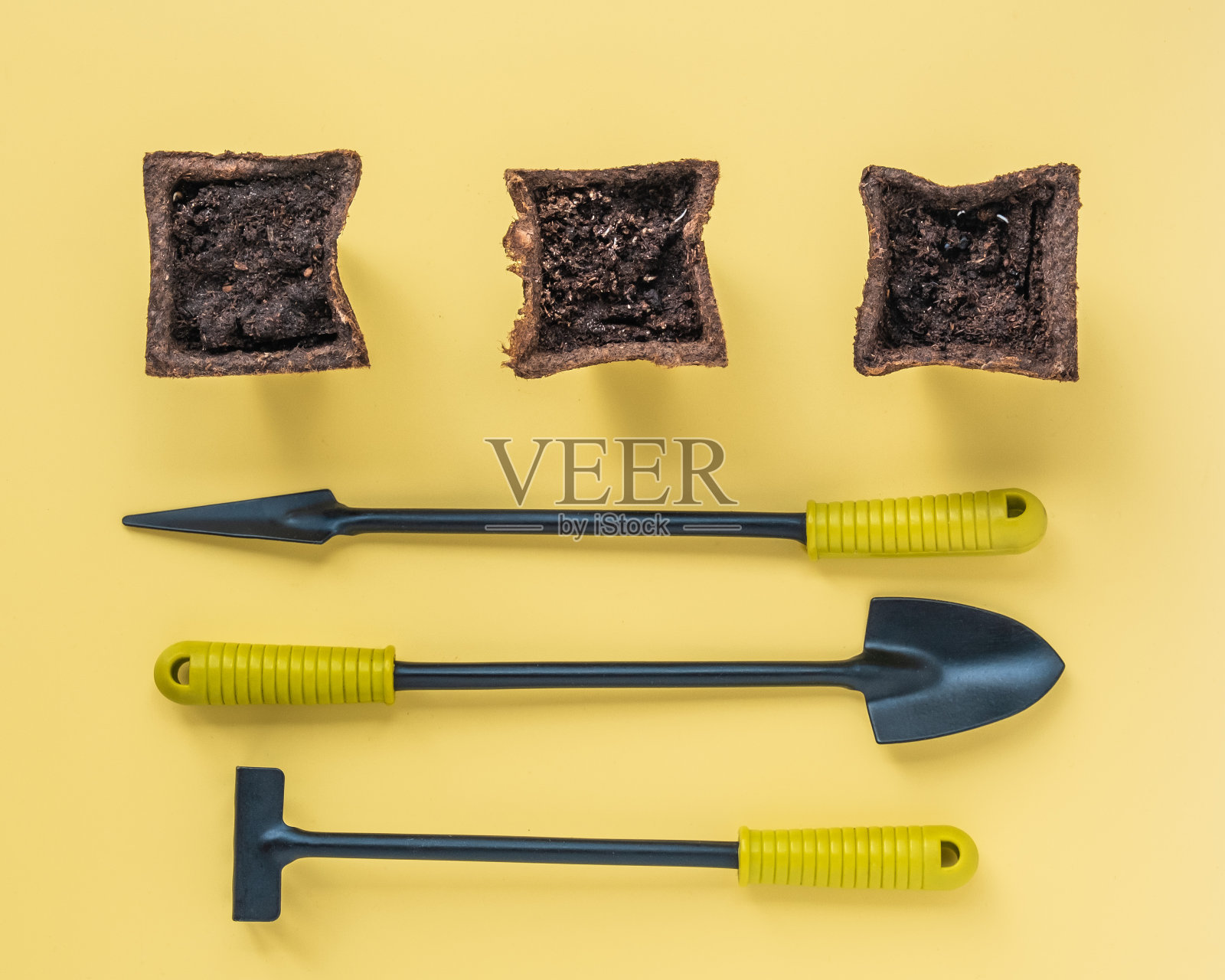 三个带种子的泥炭盆。用于家庭花园的小工具，耙子和铁锹。照片摄影图片