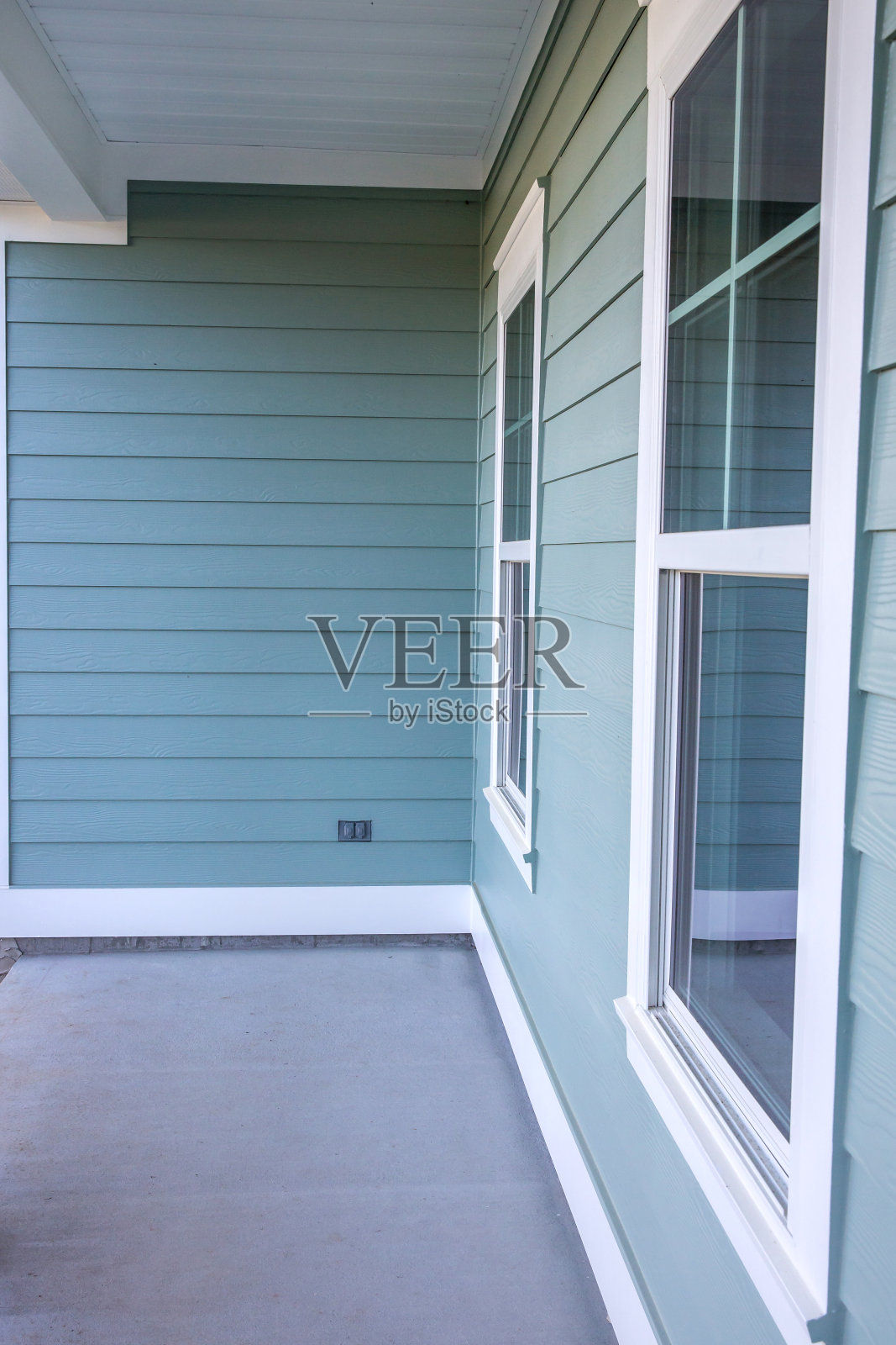 一个全新的建筑房子的小门廊的正面视图与蓝色壁板，一个牧场风格的家与一个院子照片摄影图片
