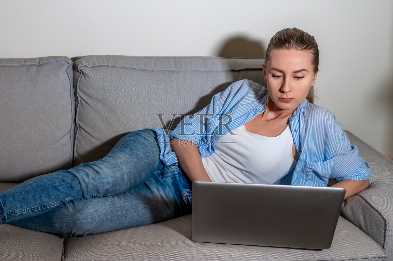 在线教育和家庭办公。在家沙发上远程工作的女性。使用电脑。自我孤立。检疫照片摄影图片