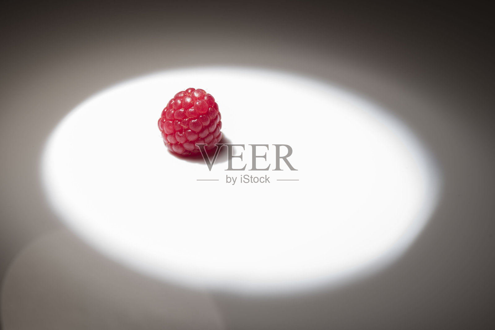 新鲜的覆盆子在白色的表面上，中间有一个较浅的圆圈。照片摄影图片