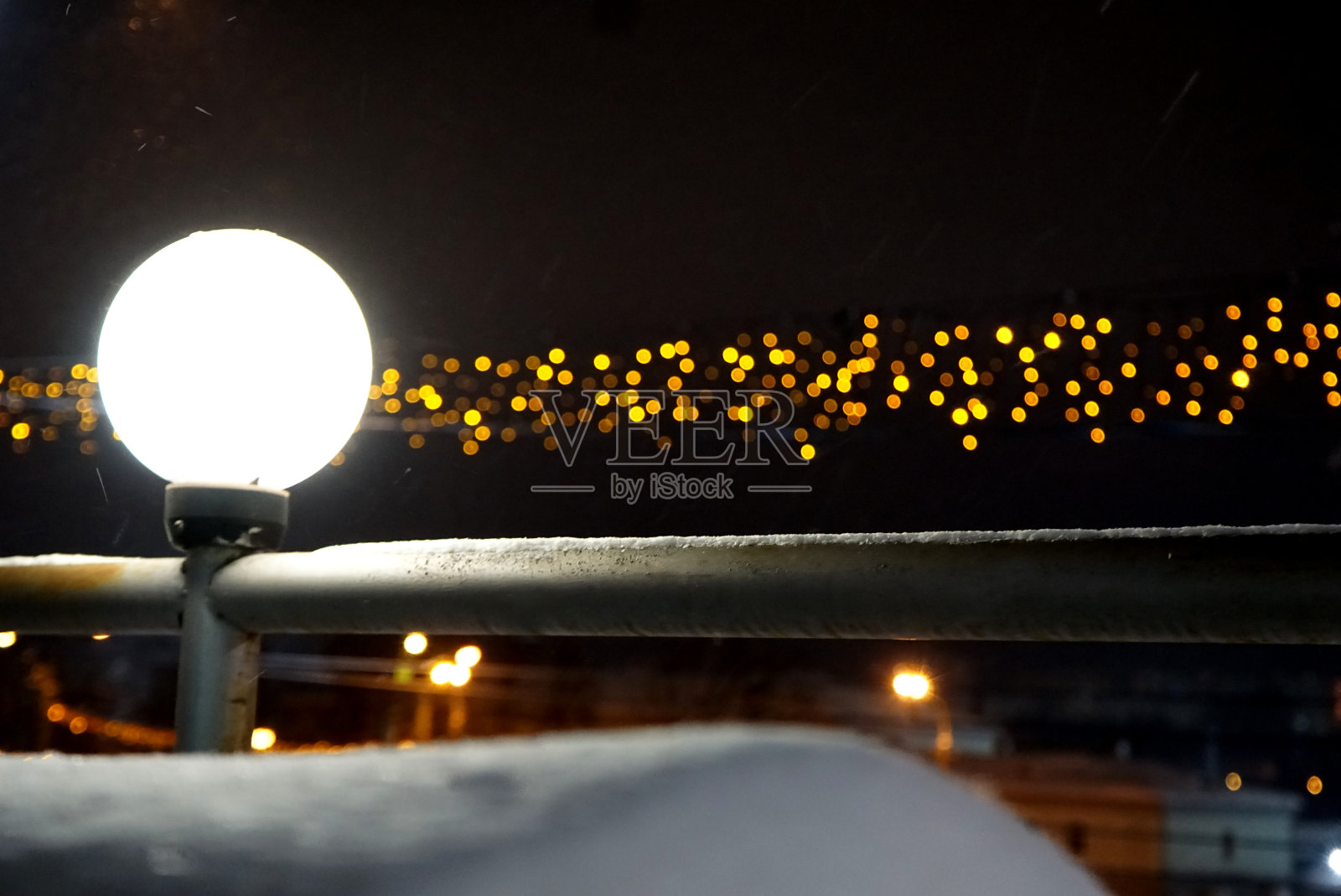 发光的球形灯笼和金色的花环在夜晚的冬季城市的背景上。照片摄影图片