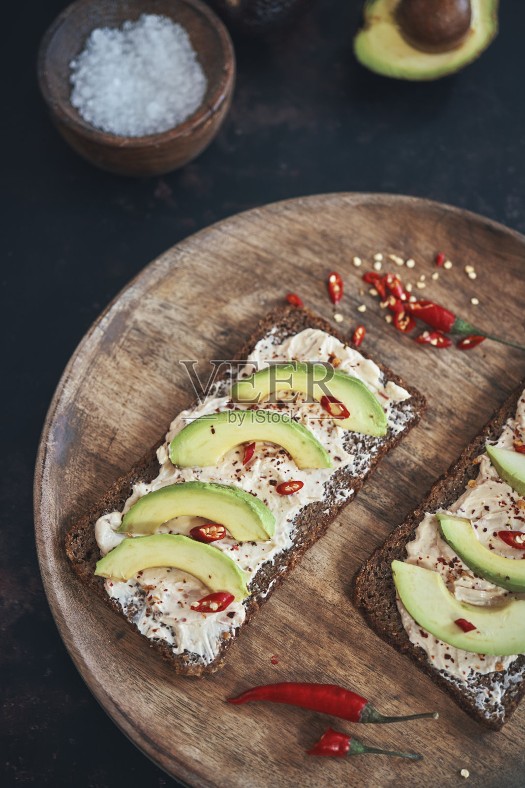 准备牛油果三明治配黑面包，白软干酪和辣椒照片摄影图片