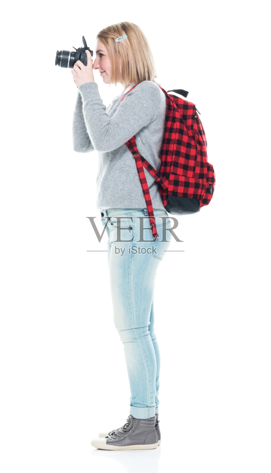 z一代女游客穿着牛仔裤，拿着相机站在白色背景前照片摄影图片