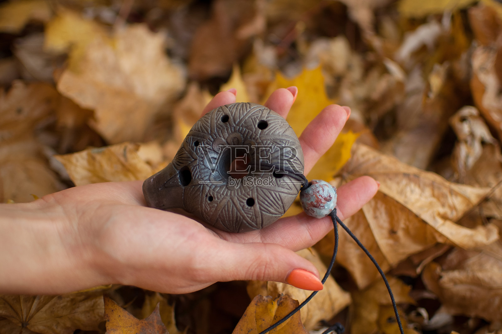 秋天的森林里，修指甲用橙色的女性手捧陶笛。轻松宁静的场景，传统的音乐理念照片摄影图片