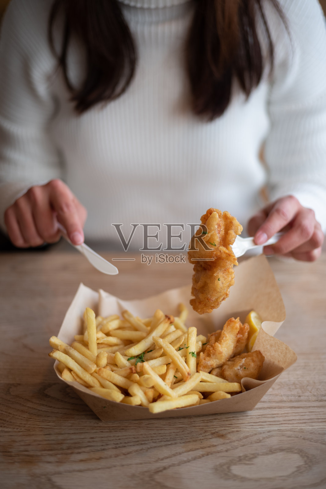年轻的亚洲妇女在快餐店吃炸鱼薯条照片摄影图片