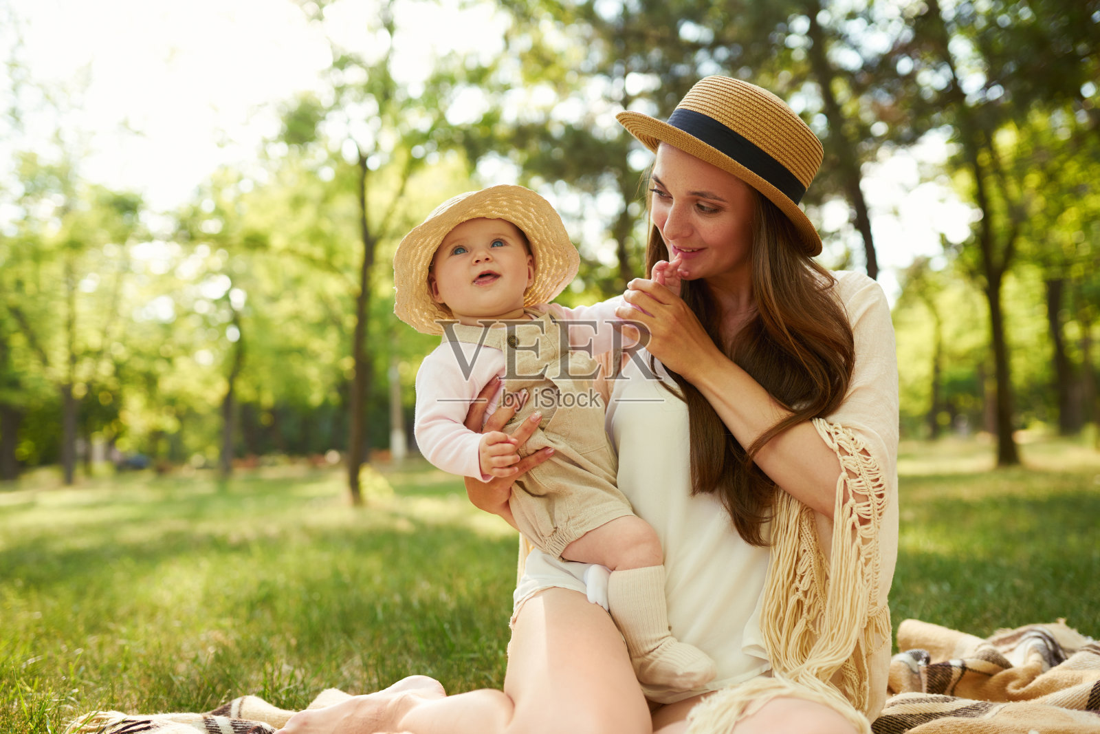 日落时分，时髦的妈妈和她的宝宝在夏日公园里玩耍。母亲节概念。照片摄影图片