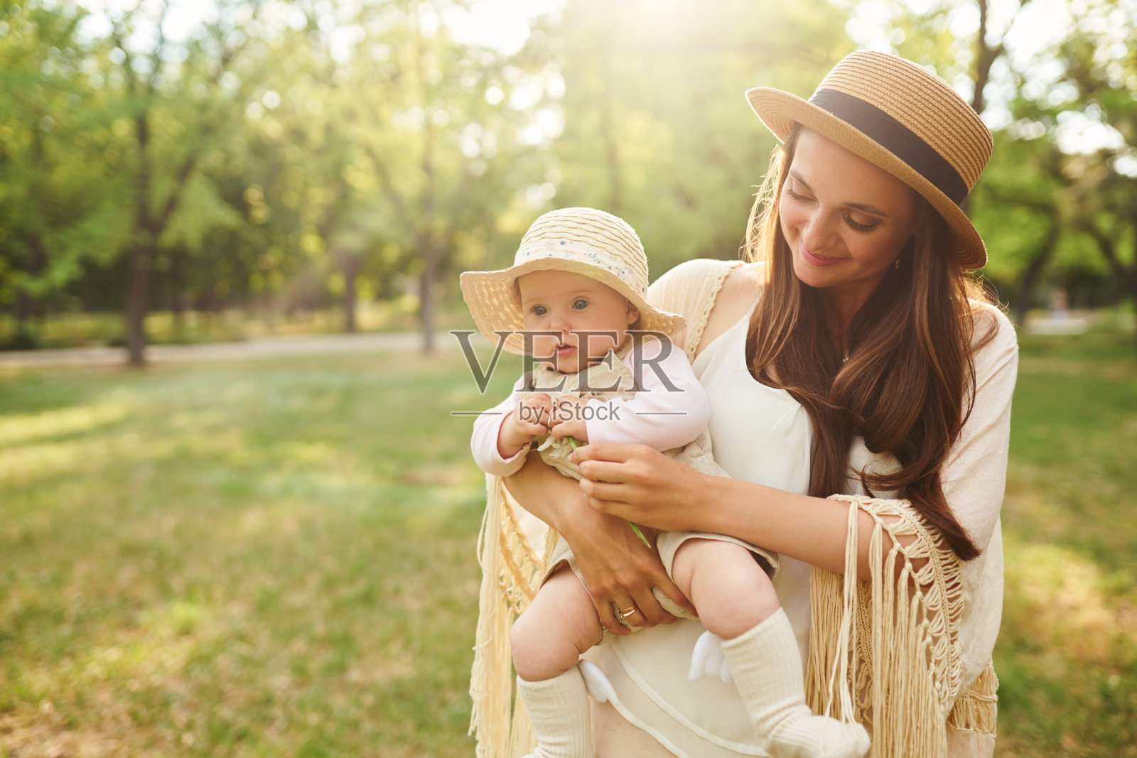 日落时分，时髦的妈妈和她的宝宝在夏日公园里玩耍。母亲节概念。照片摄影图片