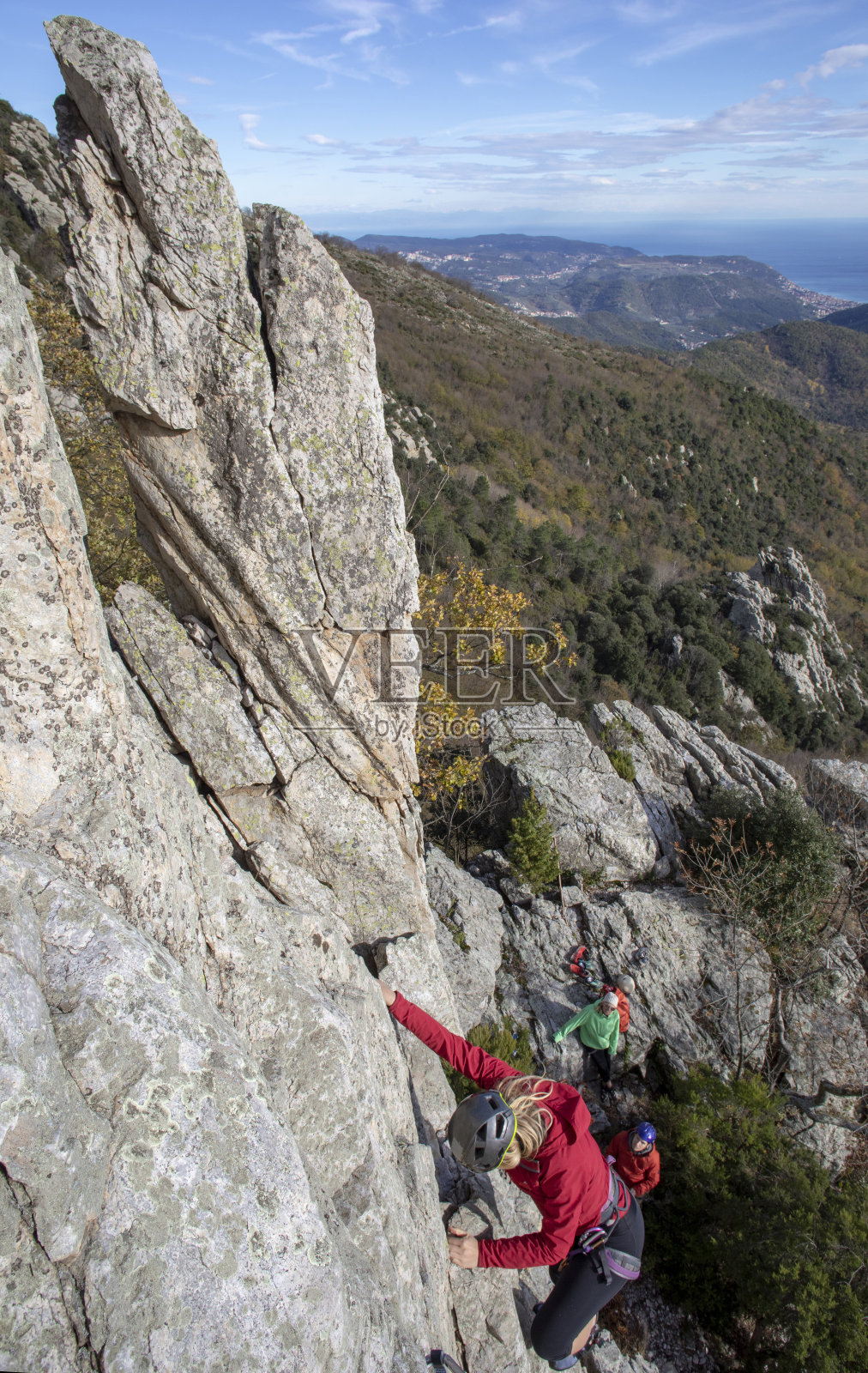 年轻女子爬上了山头，下面有家人的保护照片摄影图片