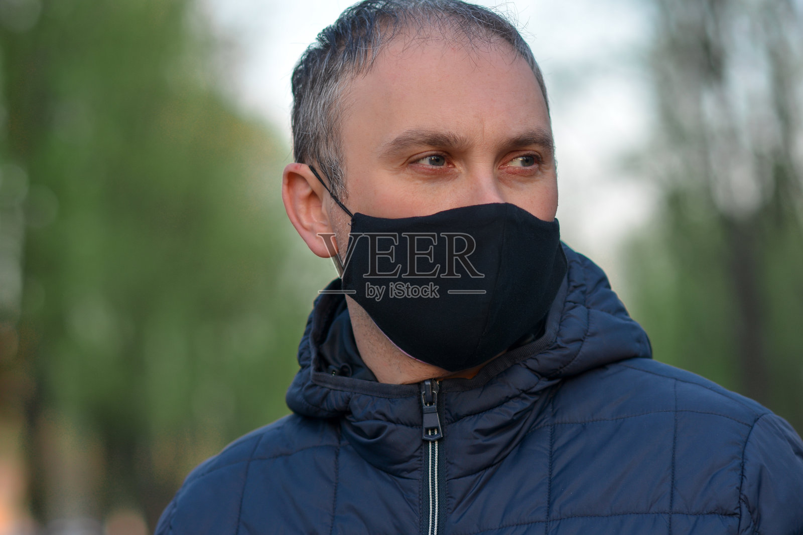 一名年轻欧洲男子的特写照片，他戴着黑色防护面具，以防止感染流感病毒或冠状病毒。空气污染、病毒、大流行冠状病毒概念。照片摄影图片