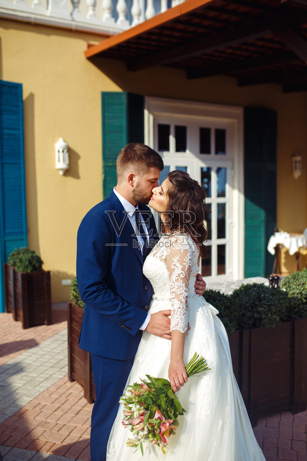 完美的新婚夫妇，新郎摆姿势亲吻。照片摄影图片