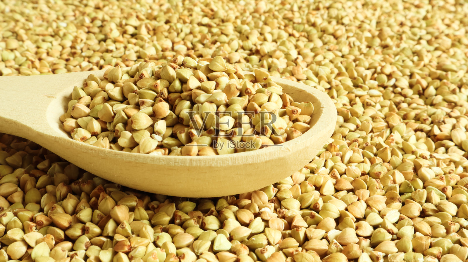 背景是荞麦，生的绿色谷物放在木勺里。健康的燕麦。有机生的非油炸素食。健康均衡饮食的概念。饮食产品。健康的燕麦照片摄影图片