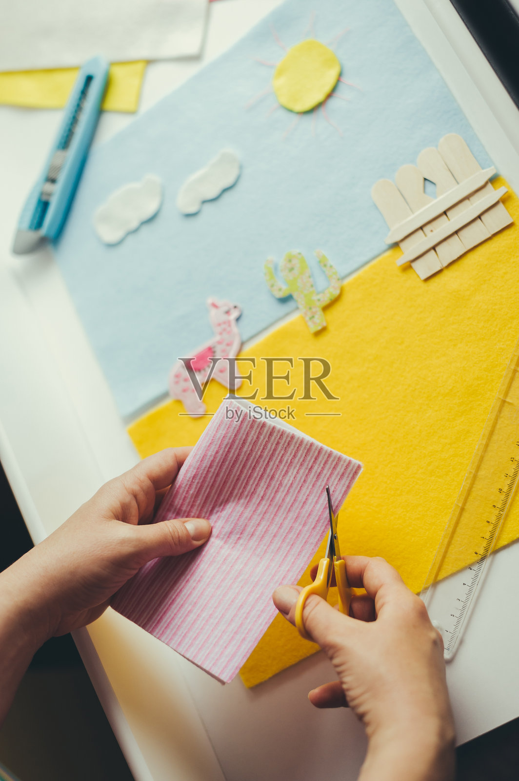 孩子在做拼贴画。从彩纸上剪出形状，粘在基础层上。用剪刀工作，提高工艺技能。照片摄影图片