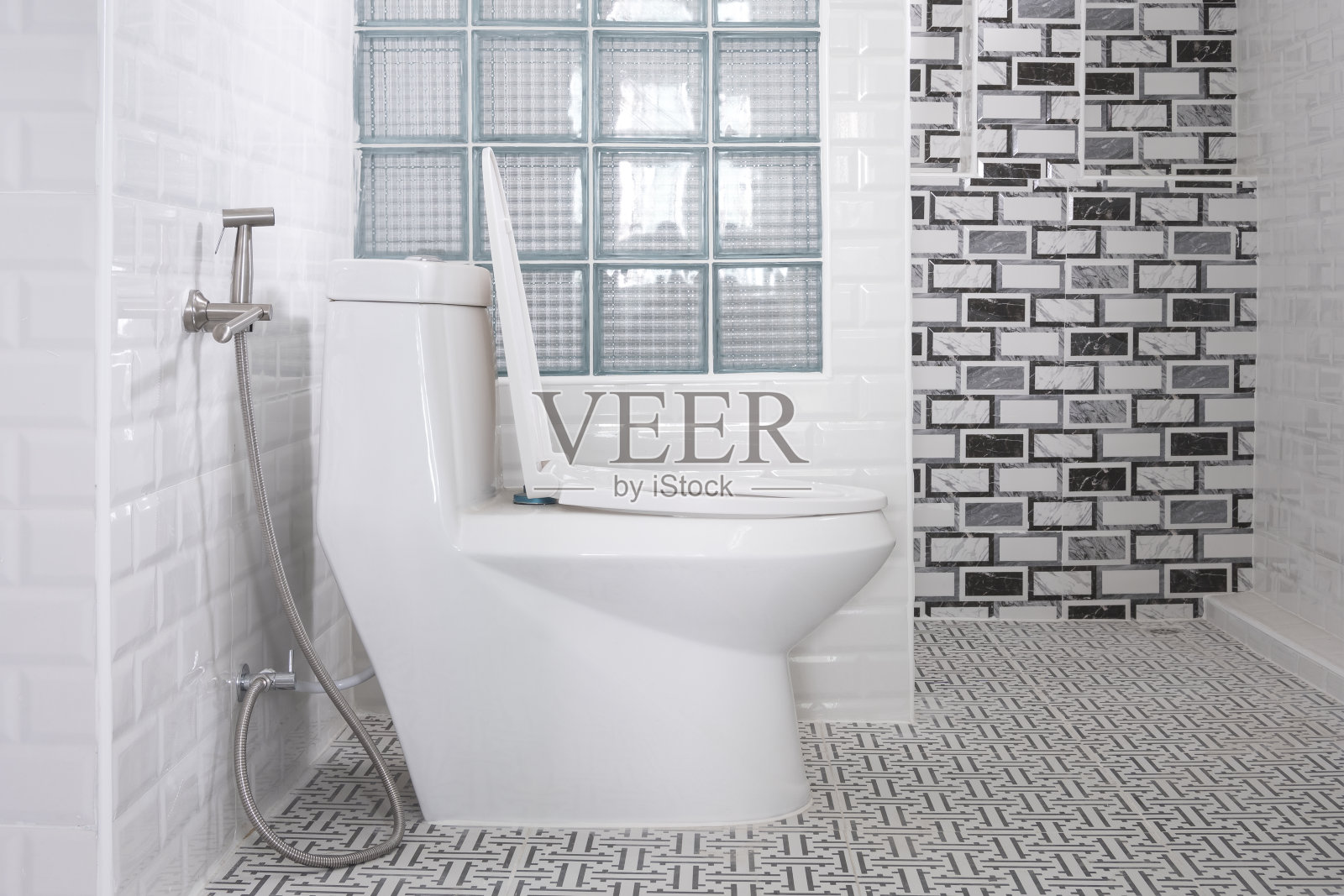 白色马桶、不锈钢坐浴盆喷淋、玻璃隔断，现代浴室内瓷砖墙面装饰照片摄影图片